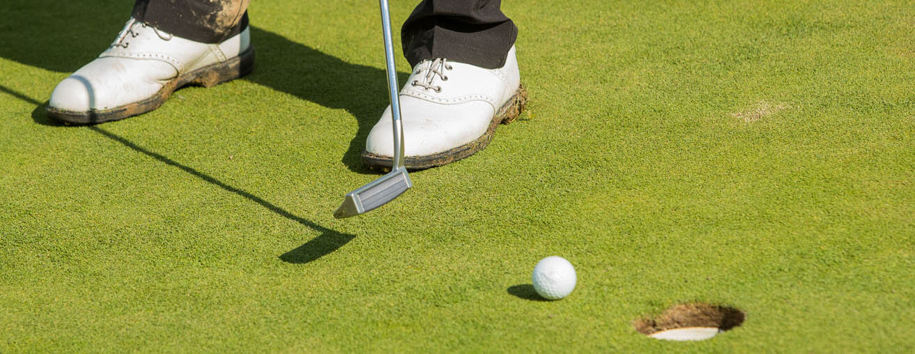 Dirty and muddy golf shoes.